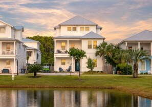 A waterfront residential area with multi-story houses, a small body of water, and greenery. - Destin Dreamin': 7 King Suites, Heated Pool, Golf Cart & Arcade Bunk Room (Miramar Beach)