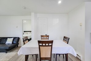 Een zithoek met een tafel en stoelen, een bank en een deur op de achtergrond.