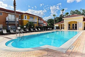 Une piscine avec des chaises longues et un bâtiment doté de balcons.