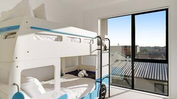 A bunk bed room with a view of a residential area through a large window.