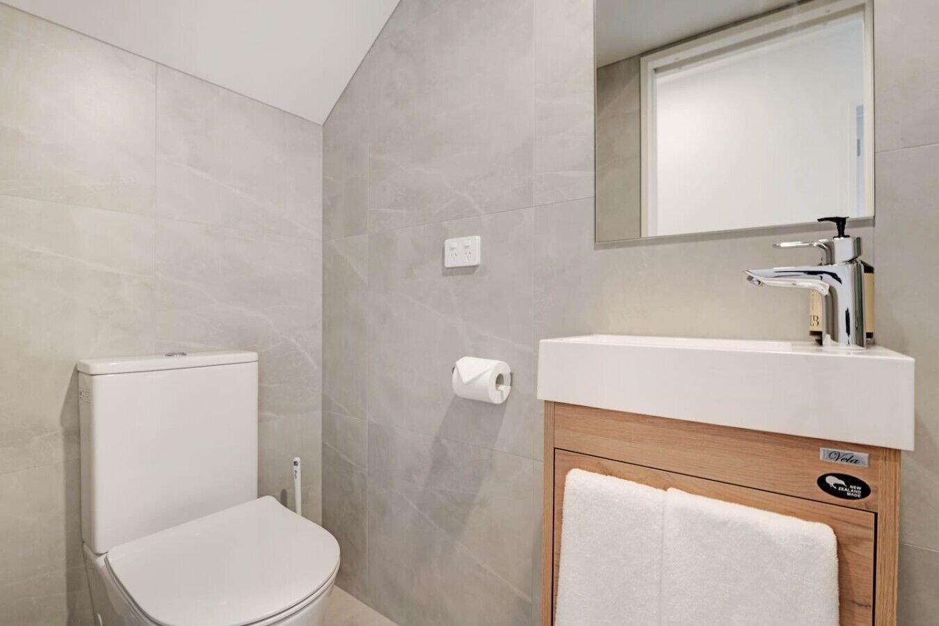 A bathroom with a toilet, a sink, and a mirror.