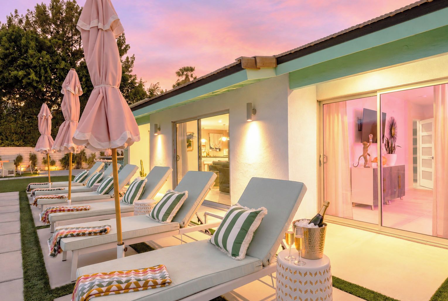 A poolside area with lounge chairs, umbrellas, and a bar area with a bottle of champagne.