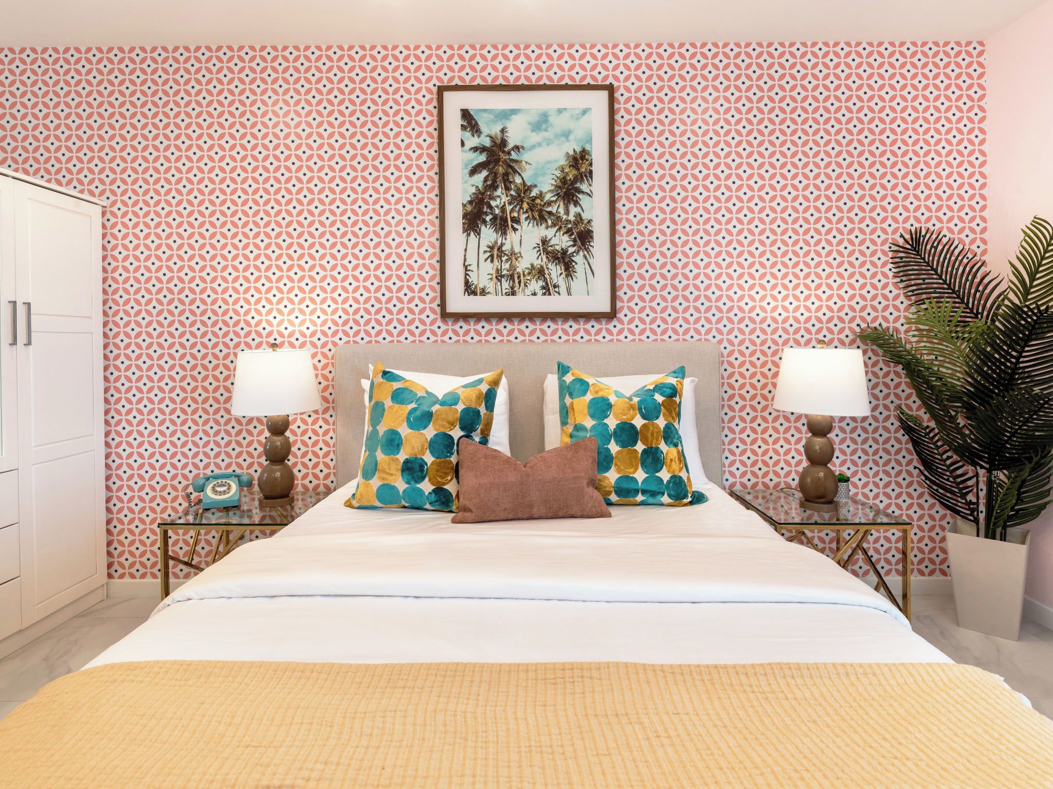A hotel room with a bed, two nightstands, a framed picture, and a potted plant.
