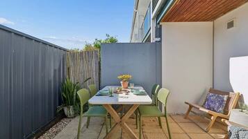 A patio with a table and chairs, a wooden fence, and a potted plant.