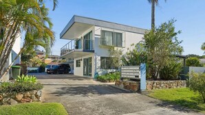 A modern two-story house with a driveway leading to a gated entrance. - Murrays Beach Studio (Sawtell)