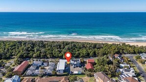 An aerial view of a coastal residential area with a red location marker. - Murrays Beach Studio (Sawtell)