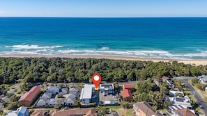 An aerial view of a coastal residential area with a red location marker. - Murrays Beach Studio (Sawtell)