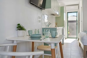 Een moderne keuken met witte kastjes, een eettafel met stoelen en een potplant.