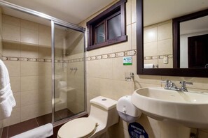 Une salle de bain équipée d’une douche à parois de verre, de toilettes, d’un lavabo avec un miroir et d’un panneau indiquant un point de dépôt.