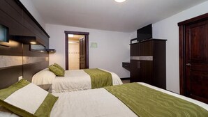 A hotel room with two beds, a wardrobe, and a television.