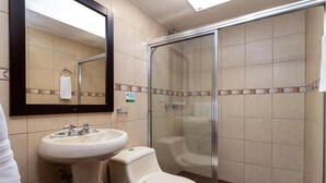 Un baño con lavamanos, inodoro y ducha con mampara de vidrio.