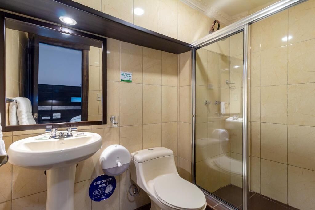 Un baño con lavabo, inodoro y cabina de ducha de vidrio.