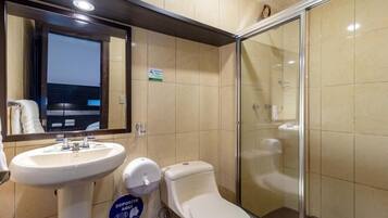 Un baño con lavabo, inodoro y cabina de ducha de vidrio.