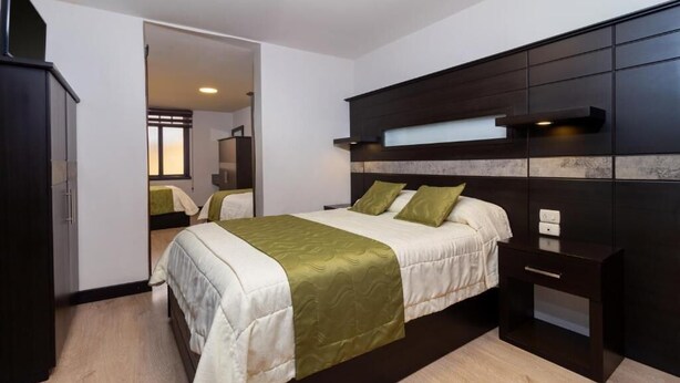 A bedroom with a bed, a wardrobe, and a nightstand.