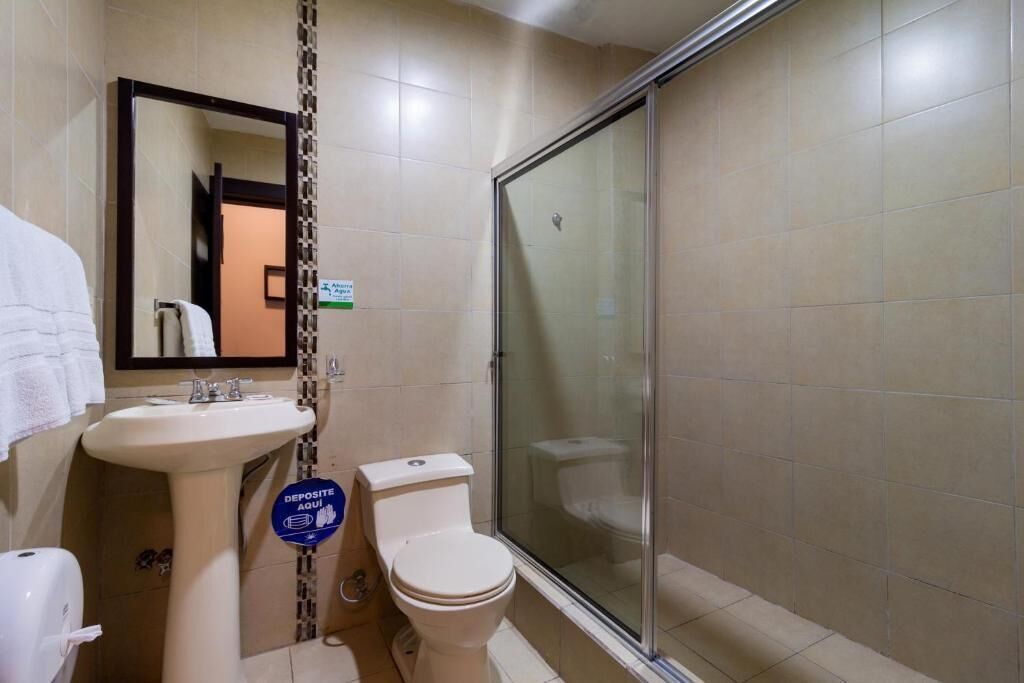 Un baño con lavamanos, inodoro y cabina de ducha con paredes de vidrio.