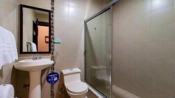 Un baño con lavamanos, inodoro y cabina de ducha con paredes de vidrio.