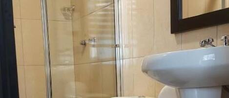 Un baño con inodoro, lavamanos y ducha.