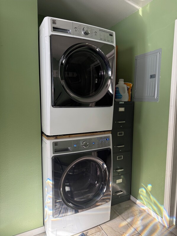 A stacked washer and dryer unit in a laundry room with green walls and a white door.