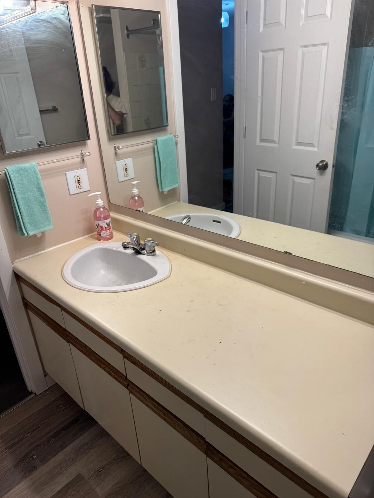 A bathroom with a sink, mirror, and a door.