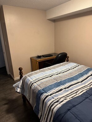 Ein Schlafzimmer mit Bett, Schreibtisch und Stuhl.