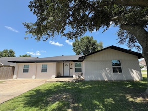A single-story house with a front porch, a garage, and a small front yard. - Tremendous 5-bedroom house in Groves perfect for group stays (Groves)
