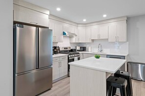 A modern kitchen with stainless steel appliances, light wood cabinetry, and a central island. - 5BR Townhouse ● 4 Ensuites ● Near U of A, Whyte & DT (Edmonton)