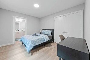 A bedroom with a bed, a desk, a chair, a wardrobe, and a mirror. - 5BR Townhouse ● 4 Ensuites ● Near U of A, Whyte & DT (Edmonton)