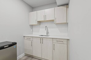 A compact kitchen with white cabinetry, a stainless steel sink, and a black dishwasher. - 5BR Townhouse ● 4 Ensuites ● Near U of A, Whyte & DT (Edmonton)