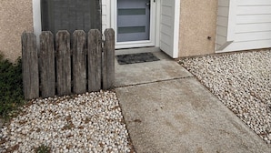 Entrada residencial con puerta de garaje, cerca de madera y camino de grava.