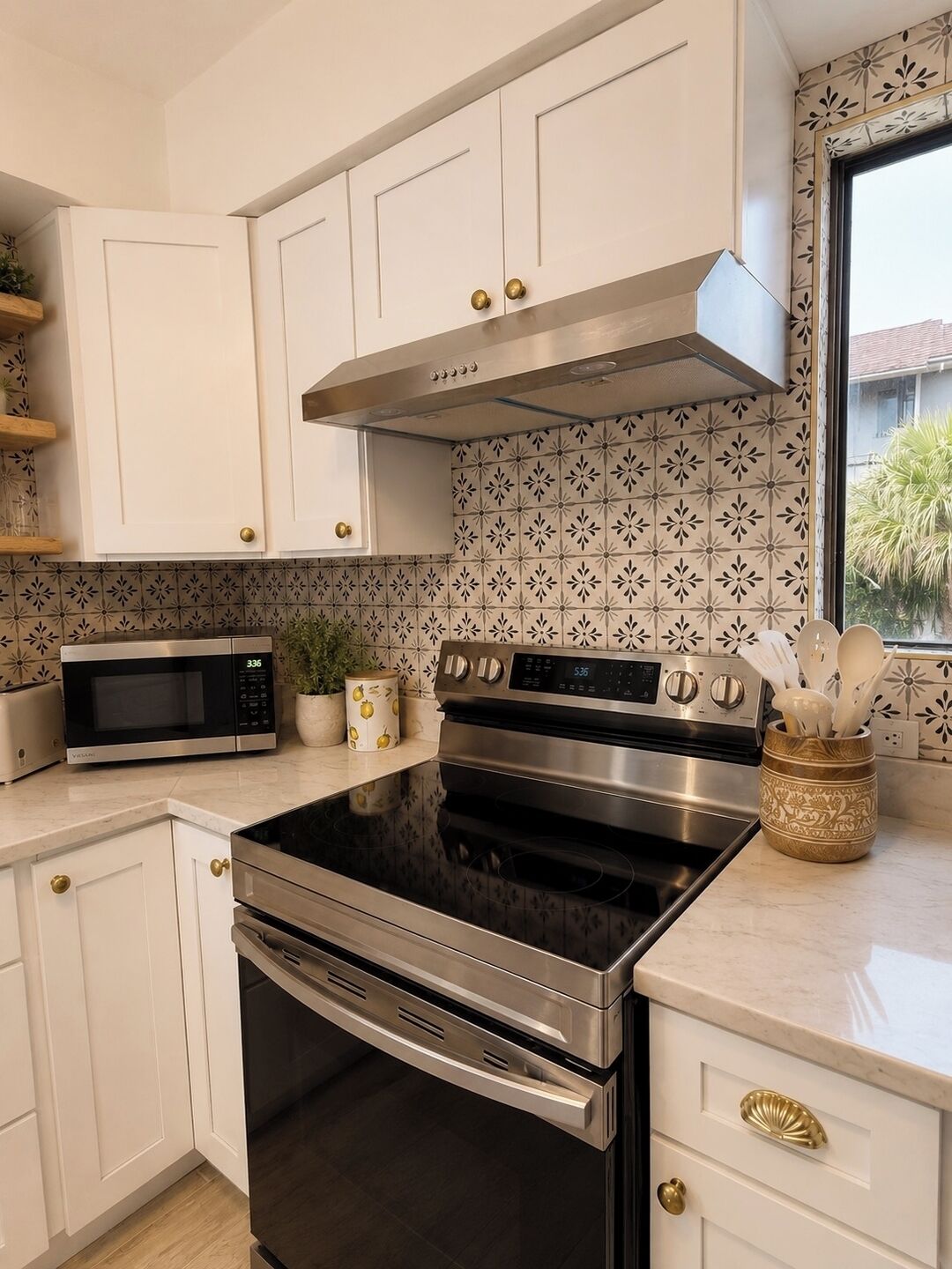 A modern kitchen with white cabinetry, stainless steel appliances, and patterned backsplash tiles.
