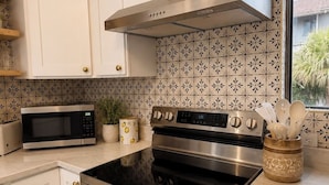 Una cocina moderna con armarios blancos, electrodomésticos de acero inoxidable y azulejos de salpicadero con diseño.