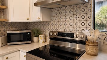 A modern kitchen with white cabinetry, stainless steel appliances, and patterned backsplash tiles.