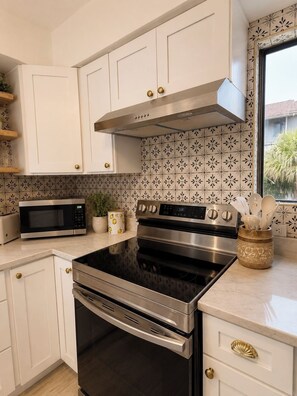 Una cucina moderna con mobili bianchi, elettrodomestici in acciaio inossidabile e piastrelle decorative a parete.