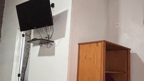 A room with a wooden ceiling, a white wall, a television mounted on the wall, and a wooden cabinet. - Stone Retreat Paraty (Paraty)