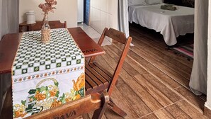 A wooden dining table with a patterned tablecloth, a vase with dried flowers, and a chair with a visible brand name. - Stone Retreat Paraty (Paraty)