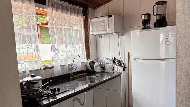 A compact kitchen with a microwave, coffee maker, and refrigerator. - Stone Retreat Paraty (Paraty)