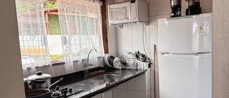 Eine kleine Küche mit Mikrowelle, Kaffeemaschine und Kühlschrank.