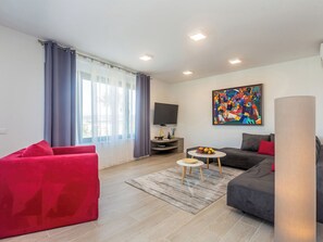 Ein modernes Wohnzimmer mit einem roten Sofa, einem grauen Sofa und einem kleinen runden Tisch mit Obst.