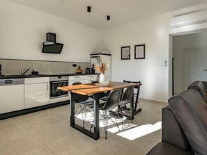 Cozinha moderna com área de refeições, com forno embutido, máquina de café e exaustor preto.