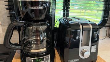 A BLACK+DECKER coffee maker and toaster on a countertop with a window in the background.