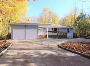 Une maison de plain-pied avec un garage, un porche à l’avant et une allée.