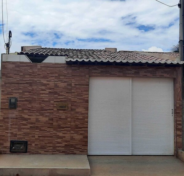 A building with a tiled roof, a brick facade, and a closed roller shutter door.