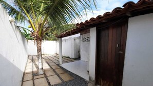 A narrow alleyway with a palm tree, a tiled pathway, and a wooden door. - Casa de praia com 2 quartos toda mobiliada para finais de semana. (Camocim)