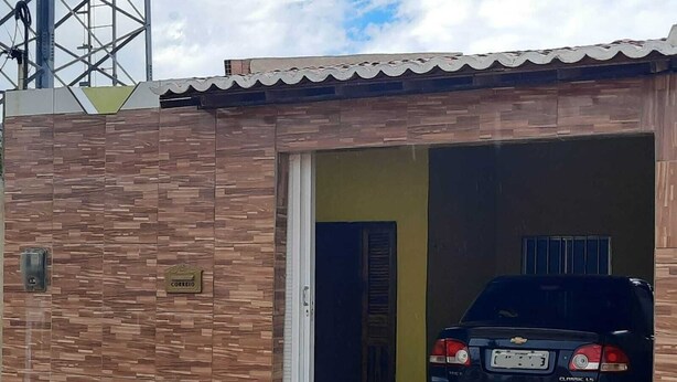 A vehicle parked inside a building with a tiled exterior wall and a door leading to a covered area. - Casa de praia com 2 quartos toda mobiliada para finais de semana. (Camocim)
