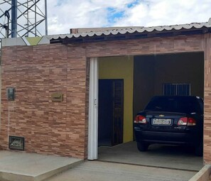 A vehicle parked inside a building with a tiled exterior wall and a door leading to a covered area.