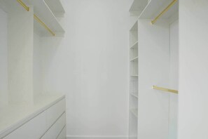 Ein weißer Kleiderschrank mit Regalen und einer Tür, versehen mit einem gelben Griff.