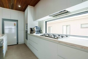 Uma cozinha moderna com fogão a gás embutido, máquina de café e geladeira.