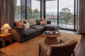 Ein modernes Wohnzimmer mit einem Ecksofa, einem runden Couchtisch, einem Korbstuhl und einer Lampe.