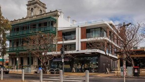 A building with a classical facade, a modern glass extension, and a flagpole. - Ocean-View Apartment in Heart of Portarlington (Portarlington)