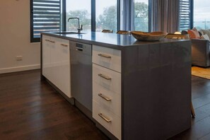Eine moderne Küche mit einer großen Kochinsel, weißen Schränken und Blick durch die Fenster.